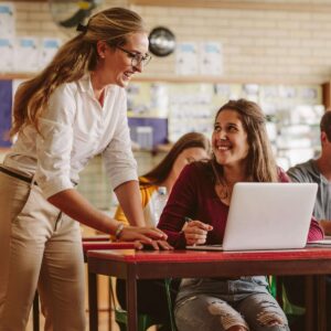 Ein Gespräch zwischen einer Lehrerin und einer Schülerin, beide lächelnd.